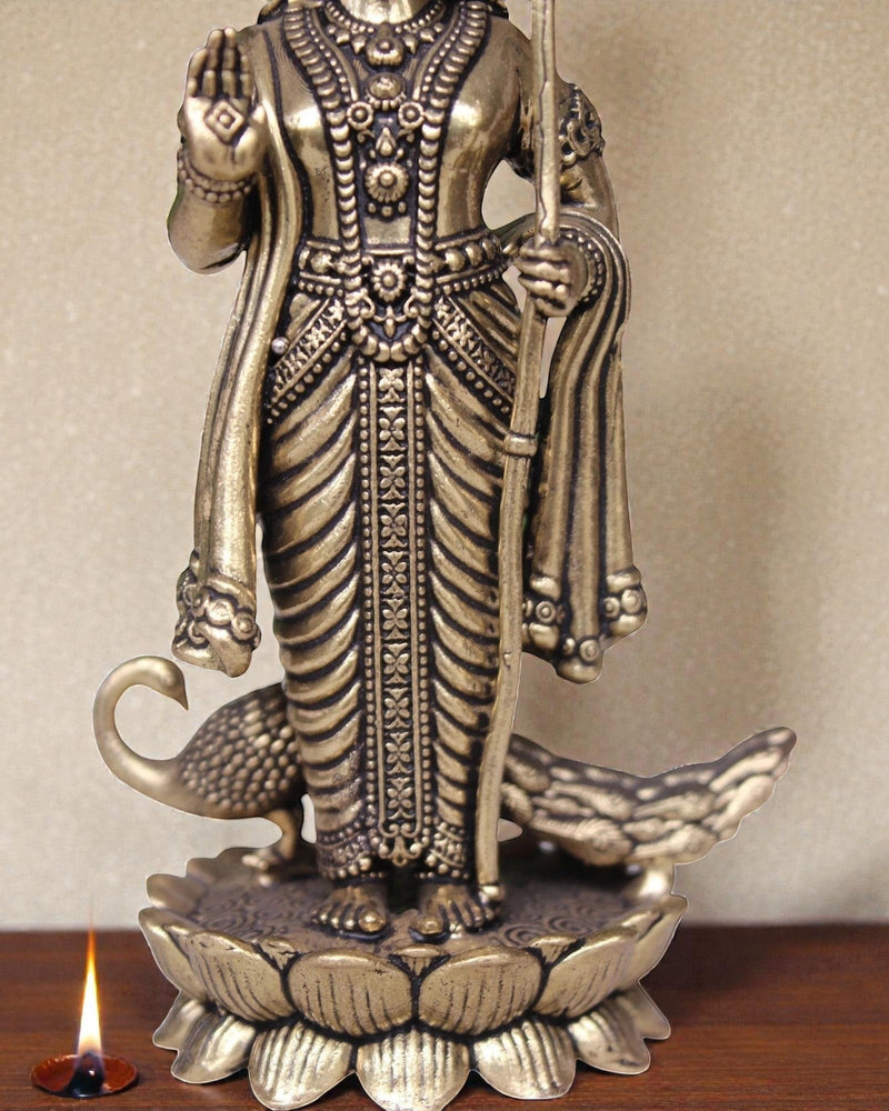 Rigvedaa brass idol of Lord Kartikeya holding a spear, standing on a lotus with peacocks. Ideal for pooja rooms.