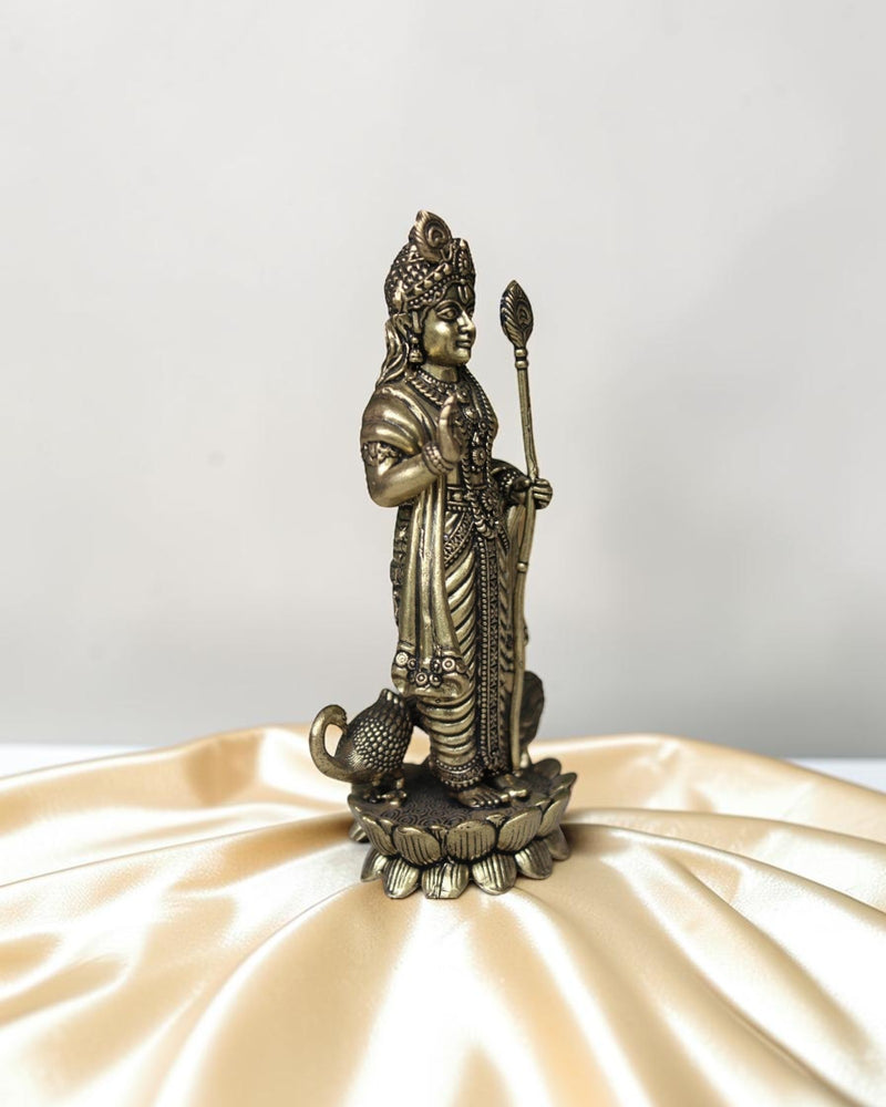 Rigvedaa brass idol of Lord Kartikeya holding a spear, standing on a lotus with a peacock at his feet. Traditional Indian deity statue.