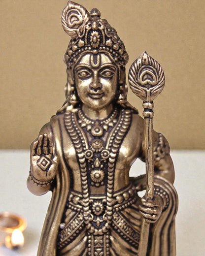 Rigvedaa brass idol of Lord Kartikeya holding a spear, adorned with intricate details and a peacock feather.