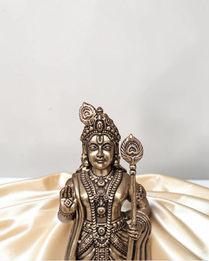 Rigvedaa brass idol of Lord Kartikeya holding a spear, adorned with intricate details and a peacock feather.