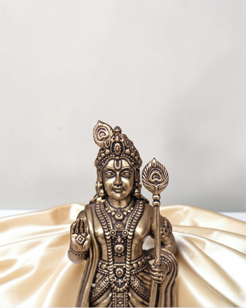 Rigvedaa brass idol of Lord Kartikeya holding a spear, adorned with intricate details and a peacock feather.