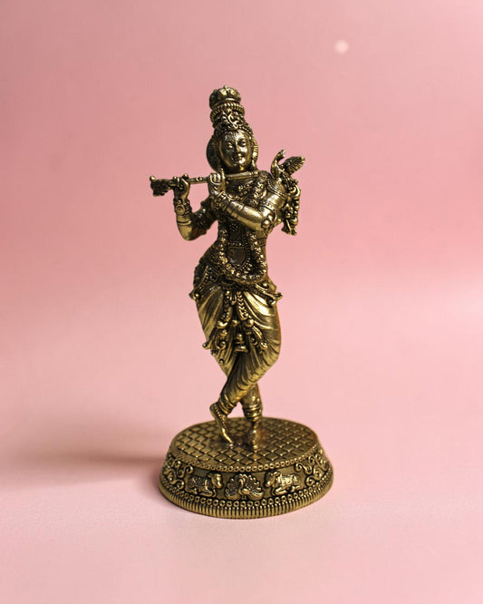 Rigvedaa™ Handcrafted brass statue of Lord Krishna playing the flute, detailed traditional attire, on a decorative base.