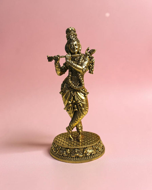 Rigvedaa™ Handcrafted brass statue of Lord Krishna playing the flute, detailed traditional attire, on a decorative base.