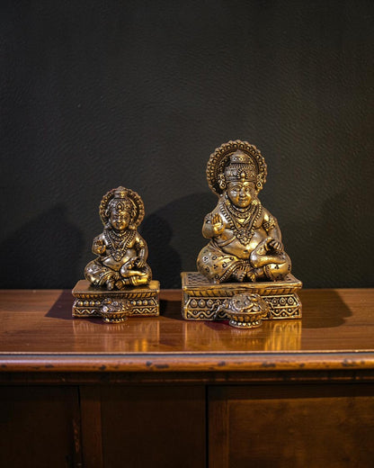 Rigvedaa™ antique brass Kuber idol seated on a decorative chowki, holding a pot of coins. Detailed ornamentation and crown.