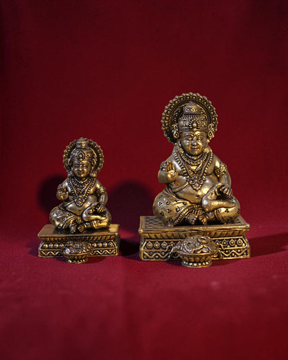 Rigvedaa™ Brass Kuber idol sitting on a chowki, holding a money pot and mongoose. Golden patina finish.