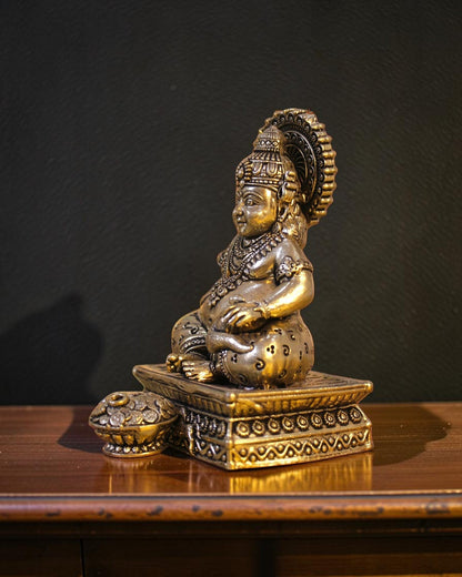 Rigvedaa brass Kuber idol seated on a decorative chowki, holding a pot of coins. Detailed ornate crown and jewelry.