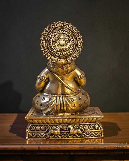 Rigvedaa brass Kuber idol sitting on a decorative chowki pedestal, adorned with ornate crown and jewelry, symbolizing wealth and prosperity.