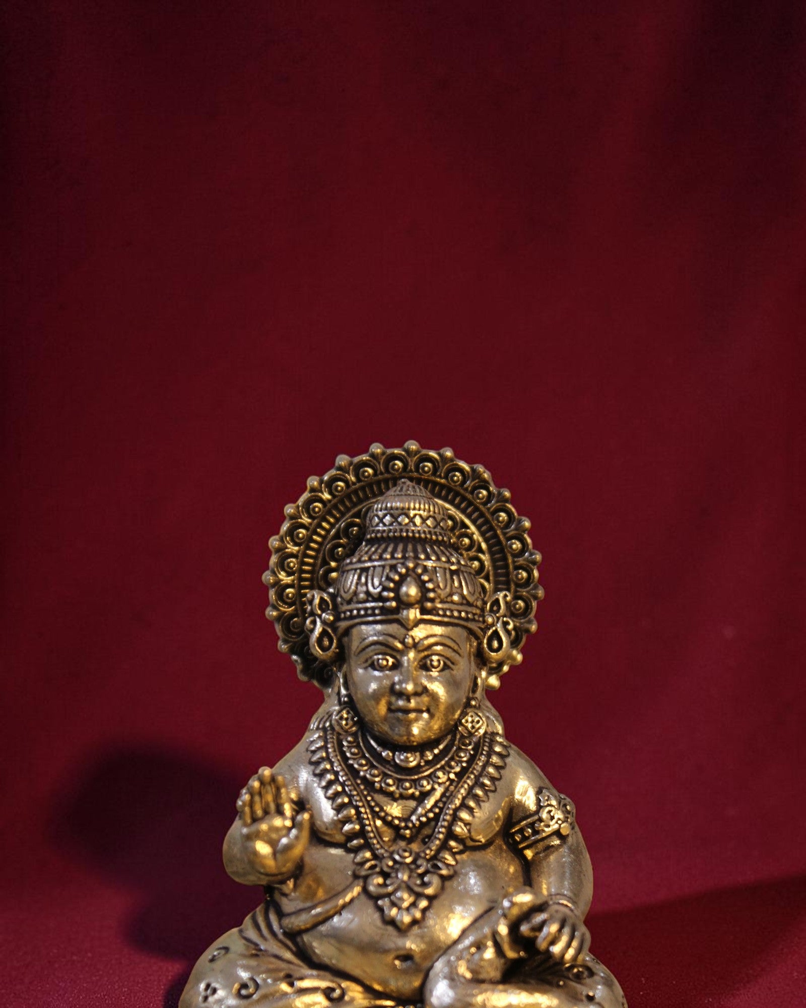 Rigvedaa™ Brass Kuber idol sitting on a chowki, holding a money pot and mongoose. Golden patina finish.