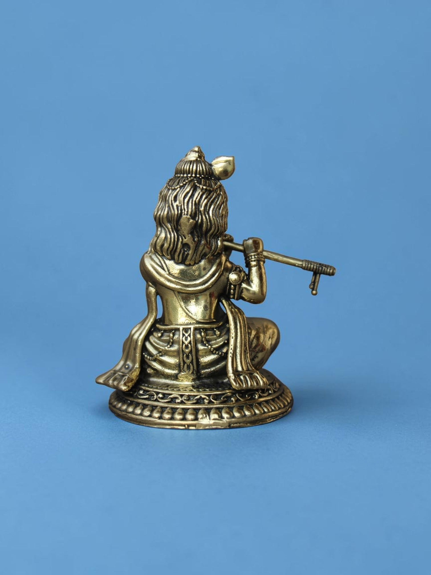 Rear view of a Rigvedaa™ brass Laddu Gopal idol showing intricate details of the peacock crown and flute