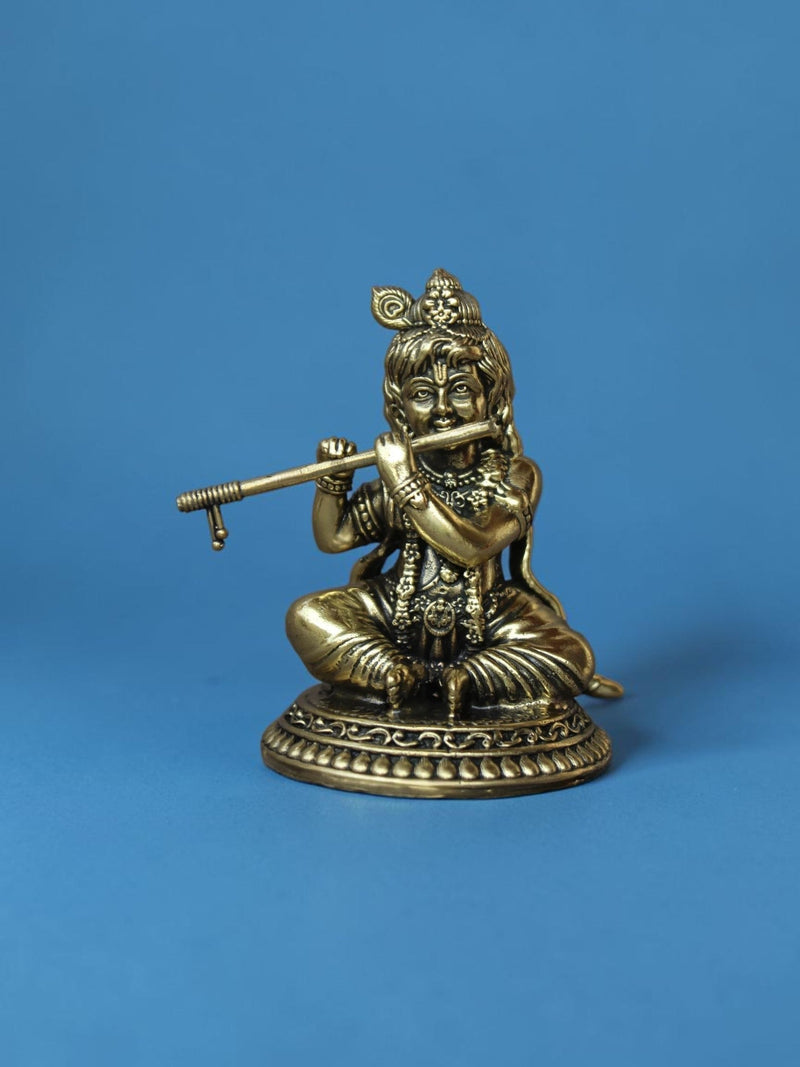 Rigvedaa™ brass Laddu Gopal idol featuring Lord Krishna playing a flute with an ornate peacock crown and golden finish.