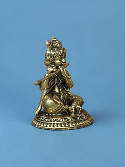 Rigvedaa™ brass Laddu Gopal idol featuring Lord Krishna playing a flute with an ornate peacock crown on a pedestal.