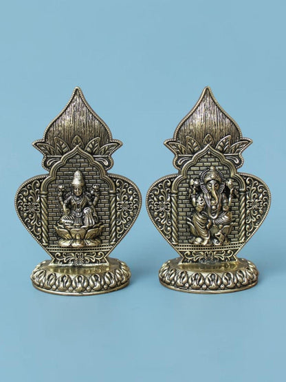 Rigvedaa™ brass Lakshmi and Ganesha idol set featuring ornate Kalash arch frames with an antique gold patina finish.