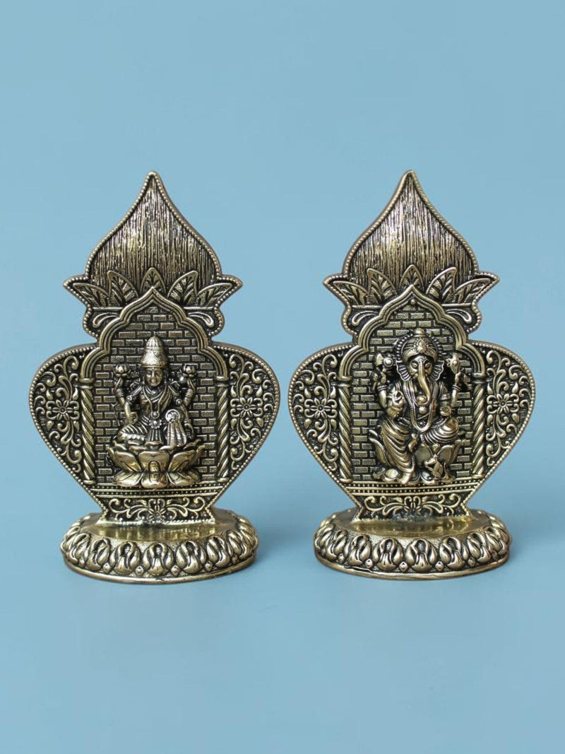 Rigvedaa™ brass Lakshmi and Ganesha idol set featuring ornate Kalash arch frames with an antique gold patina finish.