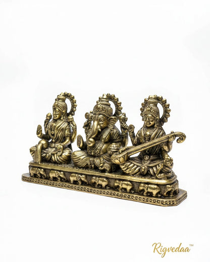 Rigvedaa brass Laxmi Ganesh Saraswati idol set, golden patina, intricate details, seated on elephant-adorned base.