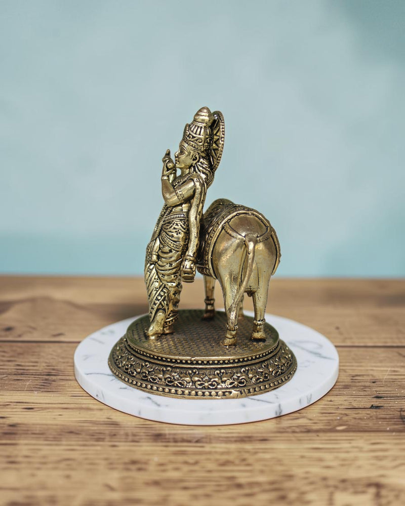 Rigvedaa™ Brass Lord Krishna with Cow Vastu Statue, 5-inch golden patina, intricate detailing, spiritual decor.