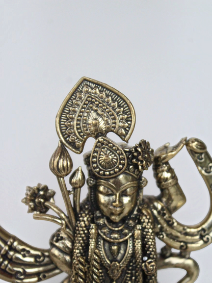 Rigvedaa™ brass Lord Vishnu idol featuring intricate antique-gold jewelry and floral motifs in a close-up view
