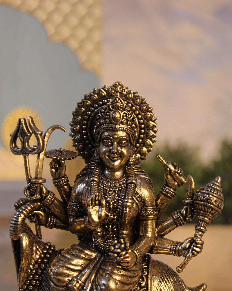 Rigvedaa™ Brass Meldi Maa statue on goat, folk goddess sculpture with multiple arms holding weapons, golden patina finish.