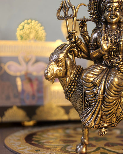 Rigvedaa™ Brass Meldi Maa statue on goat, folk goddess sculpture with intricate details and golden patina.