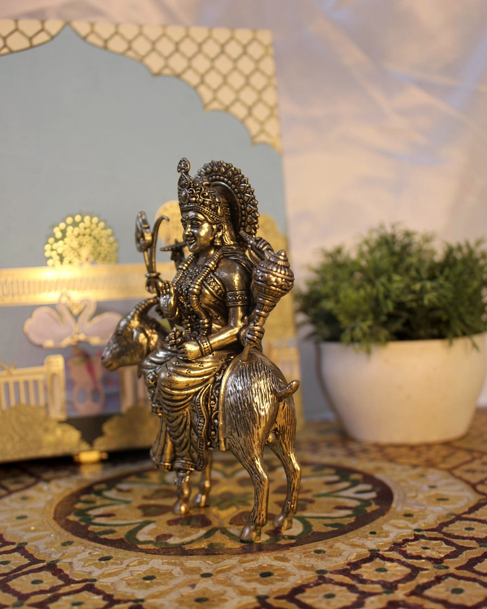 Rigvedaa™ Brass Meldi Maa statue on goat, a protective folk goddess sculpture with intricate details and golden patina.