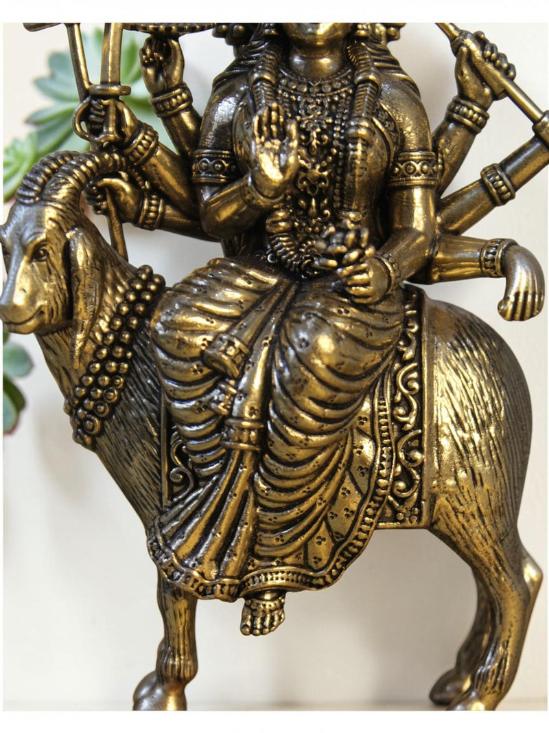 Rigvedaa™ brass Meldi Maa statue featuring the multi-armed goddess seated on a goat with a golden patina finish.