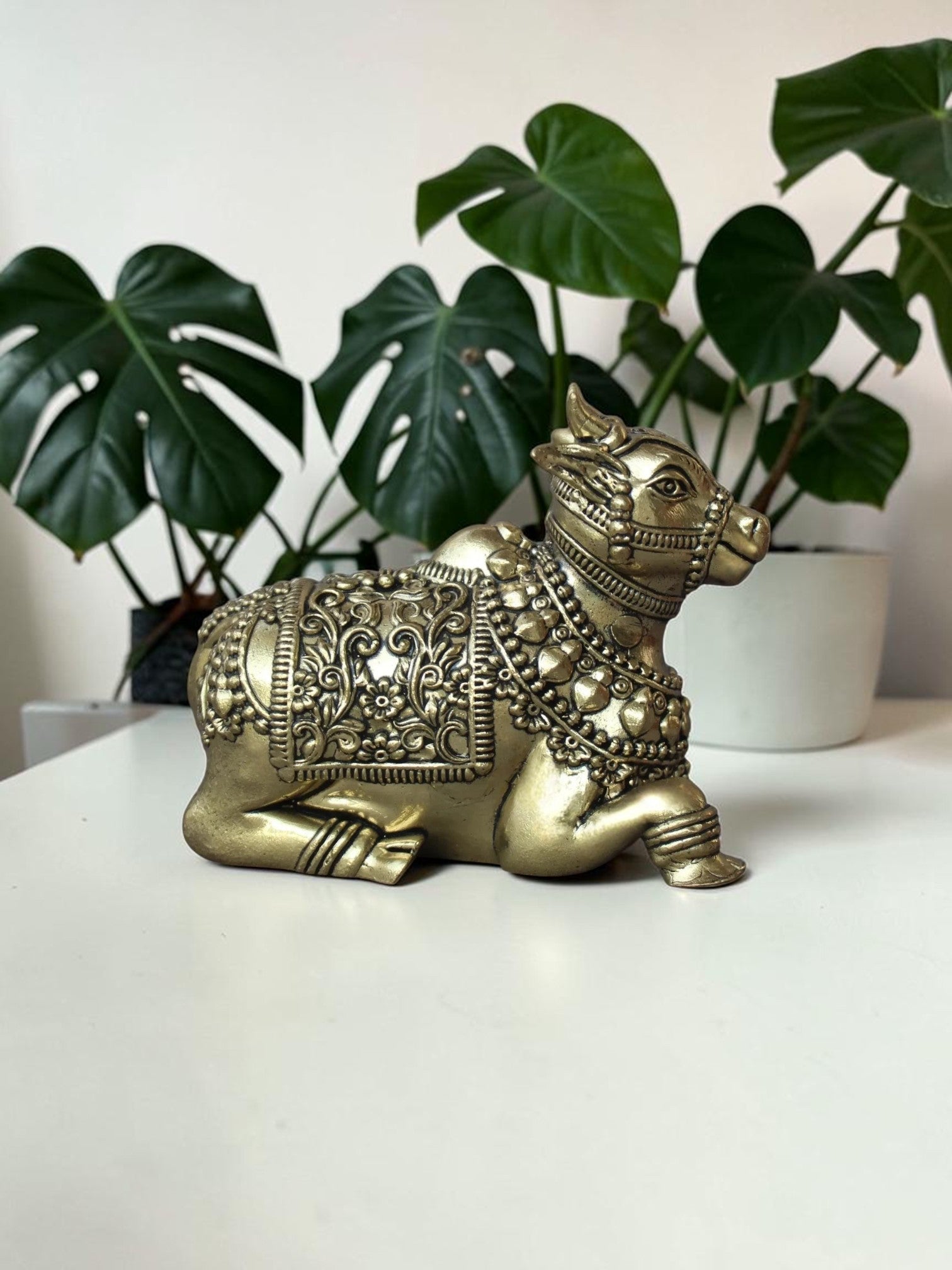 Rigvedaa™ handcrafted brass Nandi idol featuring intricate floral engravings and beadwork on a white surface.