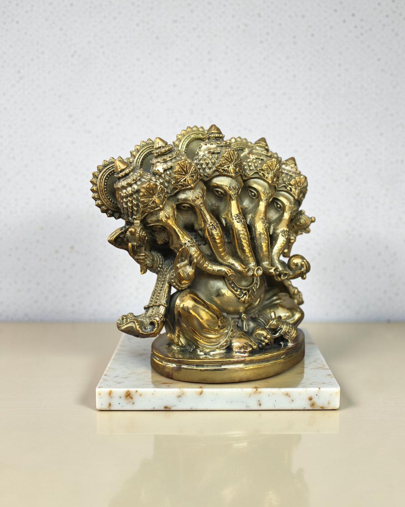 Rigvedaa™ Brass Panchmukhi Ganesha statue with five faces, intricate details, seated on a marble base. Golden patina.