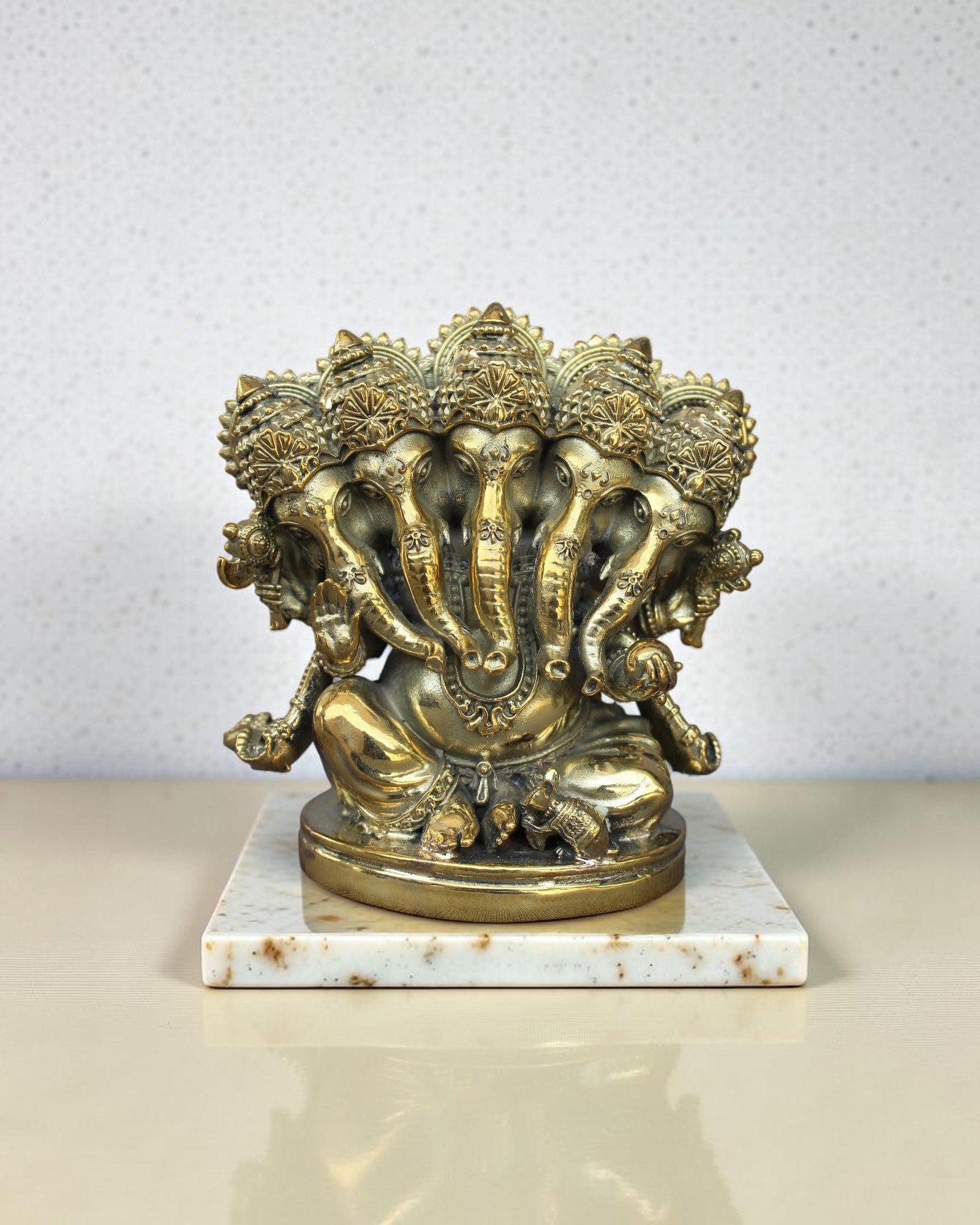 Rigvedaa™ Brass Panchmukhi Ganesha statue, five-faced Vinayaka Murti, golden patina, intricate details, seated on ornate pedestal.