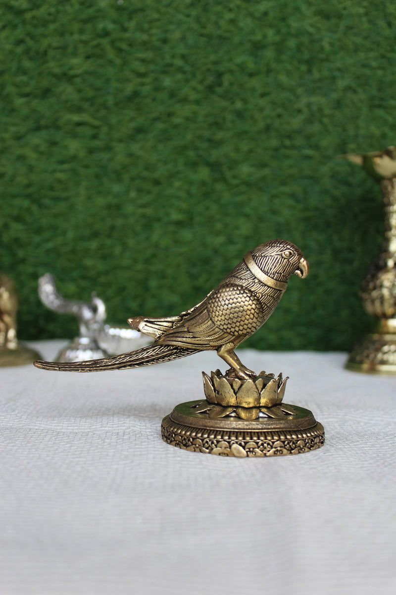 Rigvedaa™ 3-inch brass parrot figurine with intricate feather detailing, perched on a lotus base. Polished gold finish.