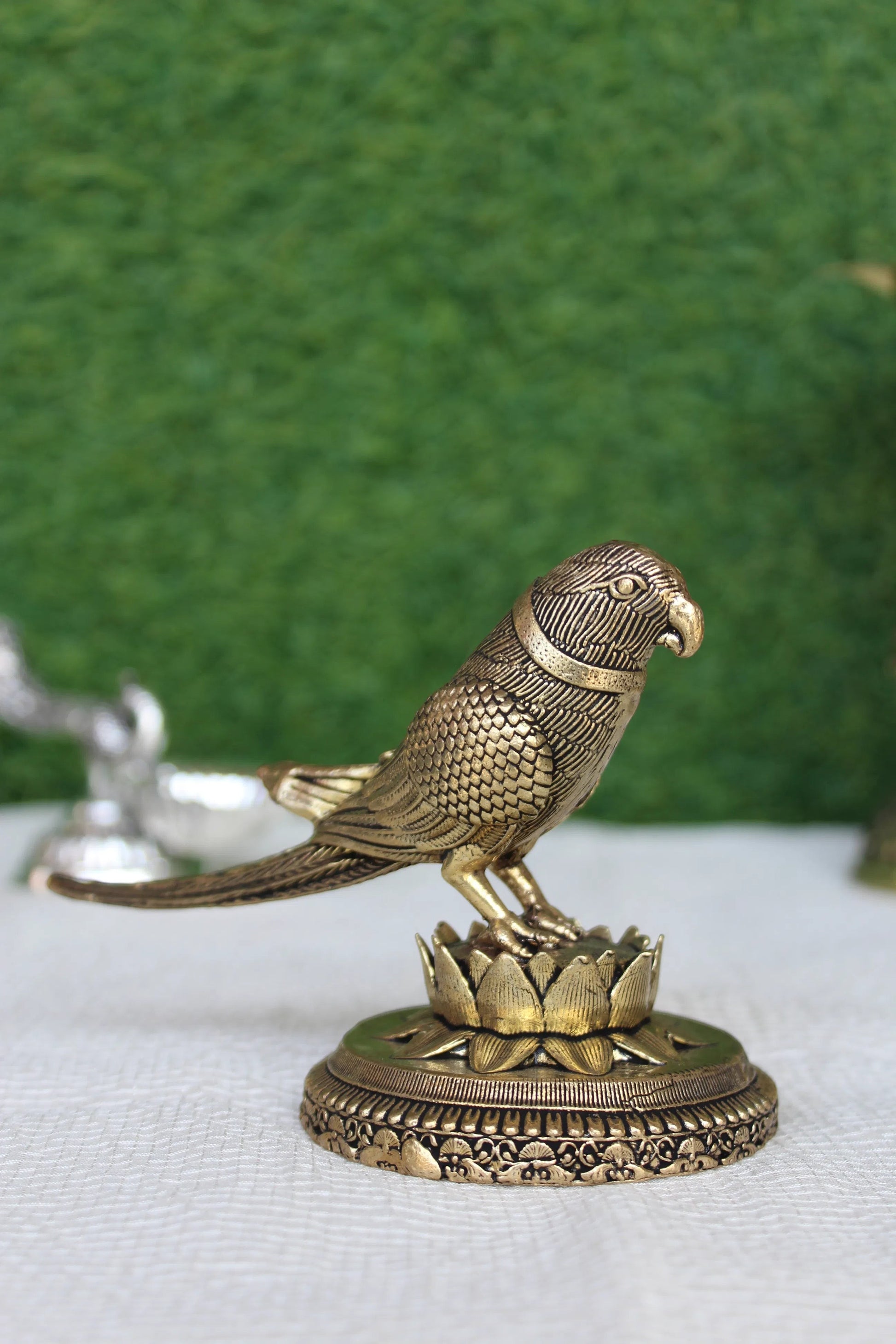 Rigvedaa™ 3-inch brass parrot figurine perched on a lotus base, featuring intricate feather detailing and a polished gold finish.