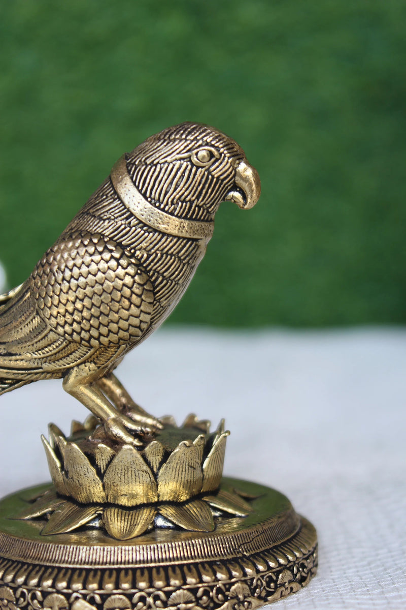 Rigvedaa™ 3-inch brass parrot figurine with intricate feather details, perched on a lotus base. Polished gold finish.