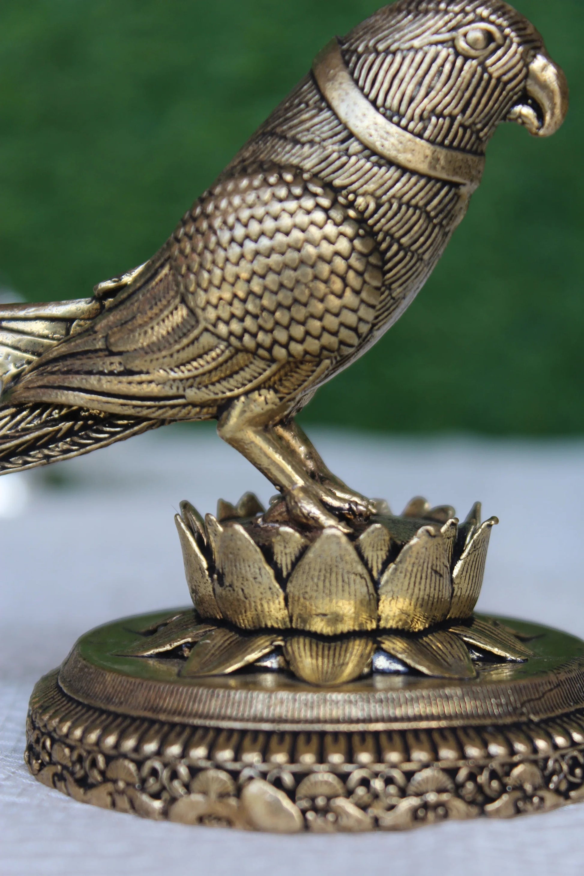Rigvedaa™ 3-inch brass parrot figurine with intricate feather detailing, perched on a lotus base. Polished gold finish.