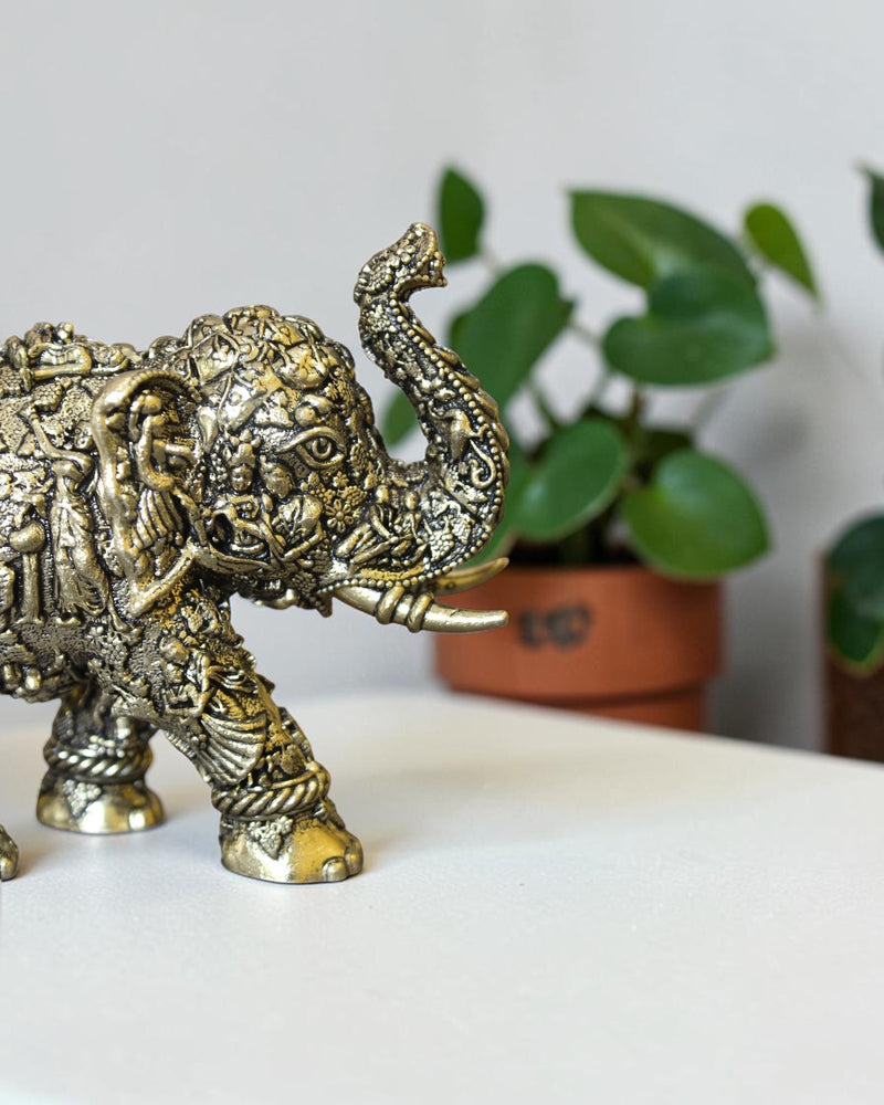 Rigvedaa™ brass elephant statue with intricate hand-carved Radha Krishna murals and a radiant golden antique finish.