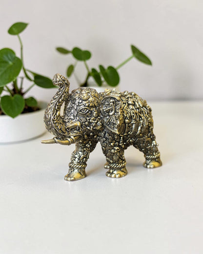 Rigvedaa™ brass elephant statue with intricate hand-carved Radha Krishna murals and a raised trunk for home decor.