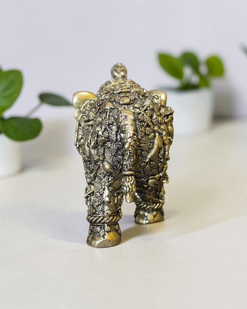 Rear view of a Rigvedaa™ brass elephant statue featuring intricate hand-carved Radha Krishna murals and golden patina.