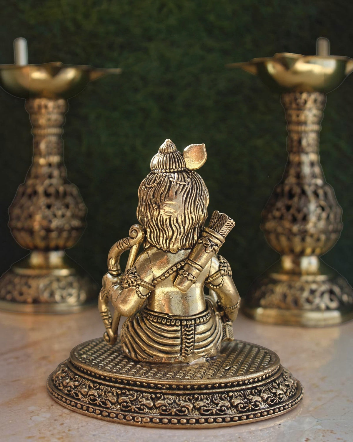 Rigvedaa™ brass Ram Lalla idol seen from behind, showing detailed hair, quiver, and bow on a decorative base.