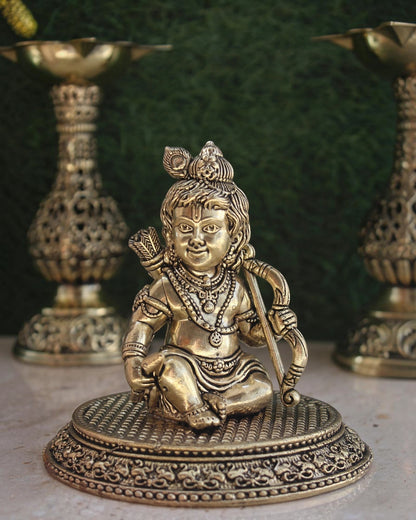 Rigvedaa™ handcrafted brass Ram Lalla idol featuring intricate Bal Ram details, crown, and bow on a textured base.