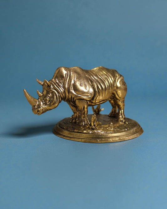 Rigvedaa™ brass rhinoceros statue, 3.25 inches, detailed golden patina, symbolizing protection and wealth.