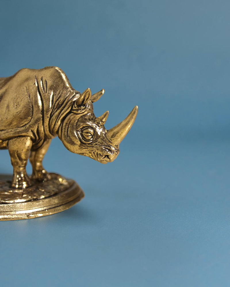 Rigvedaa™ brass rhinoceros statue, 3.25-inch, golden patina, detailed armor skin, Vastu and Feng Shui symbol for protection and wealth.