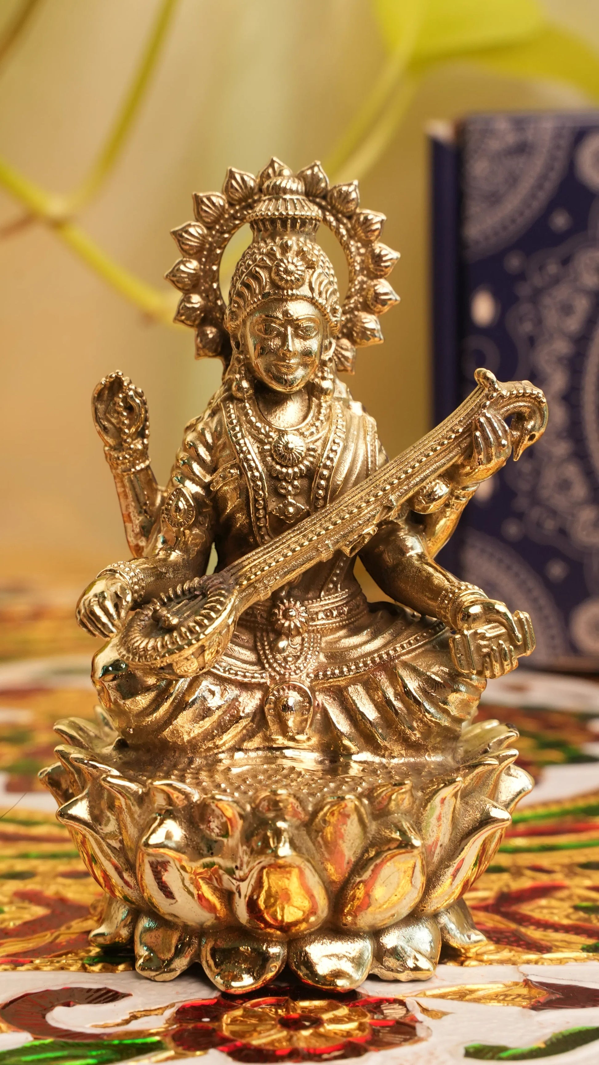 Rigvedaa™ brass Saraswati idol seated on lotus, holding veena and scriptures. Symbolizes knowledge and creativity.
