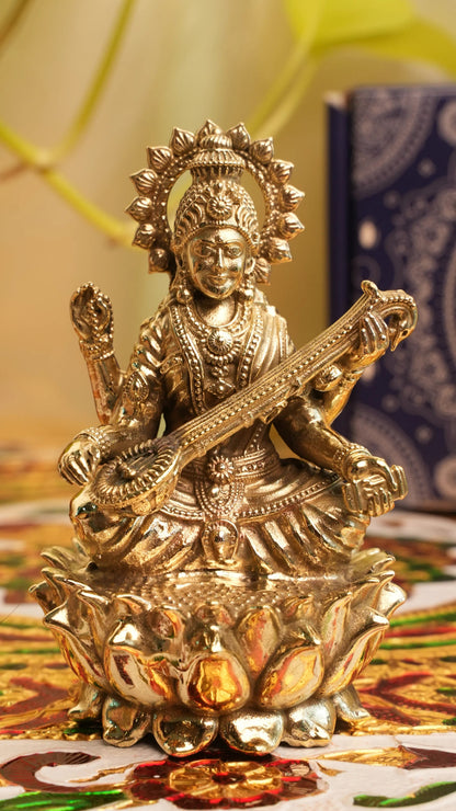 Rigvedaa™ brass Saraswati idol seated on lotus, holding veena and scriptures. Symbolizes knowledge and creativity.