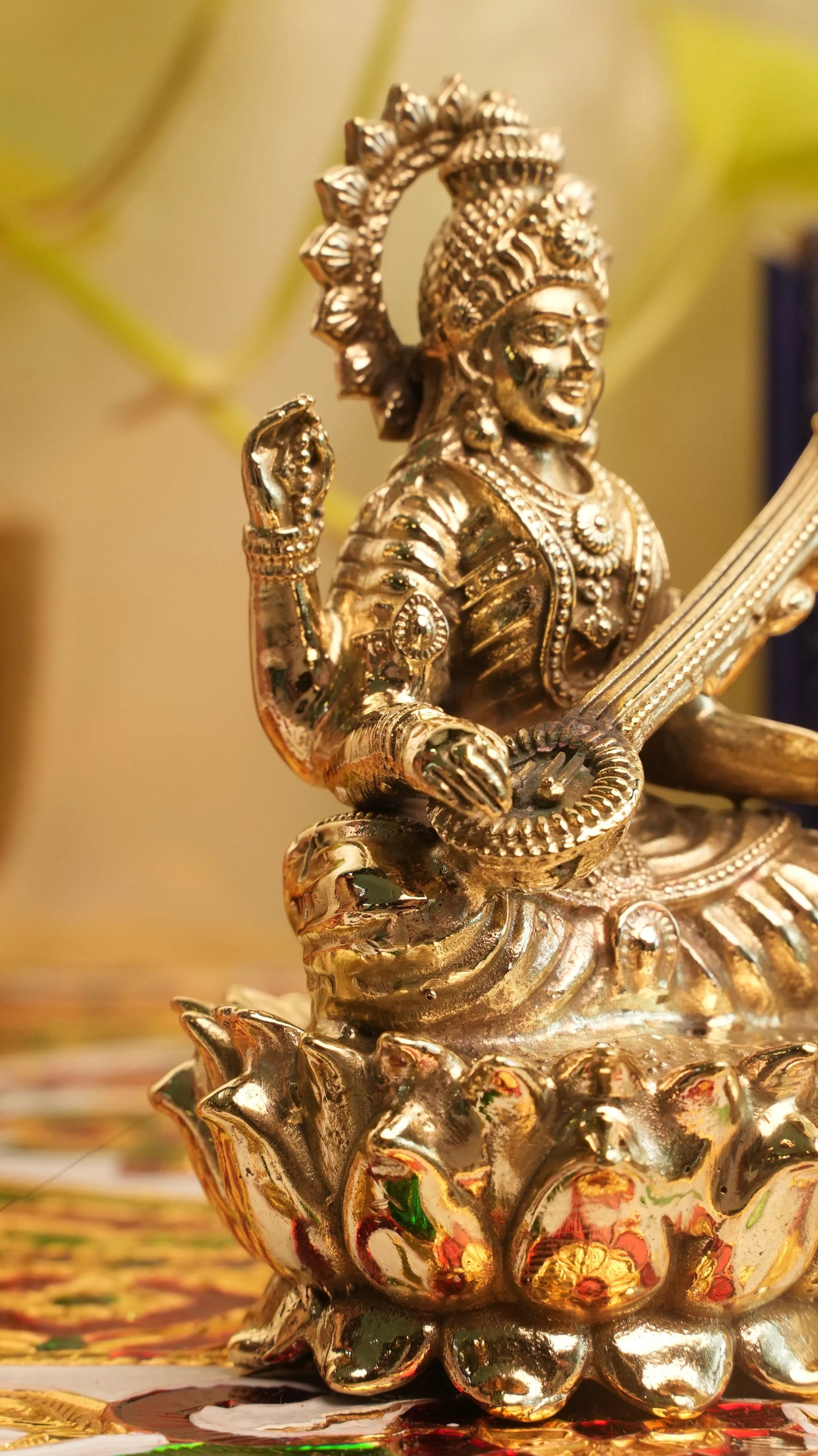 Rigvedaa™ brass Saraswati idol seated on a lotus, holding a veena and scriptures. Detailed, golden finish.