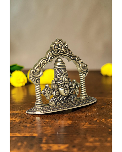 Rigvedaa brass Tirupati Balaji face murti with ornate crown and detailed ornaments, set within an arched frame.