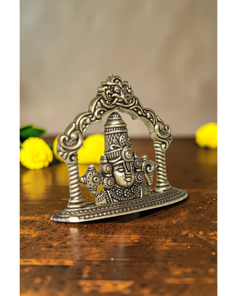 Rigvedaa brass Tirupati Balaji face murti with ornate crown and detailed ornaments, set within an arched frame.