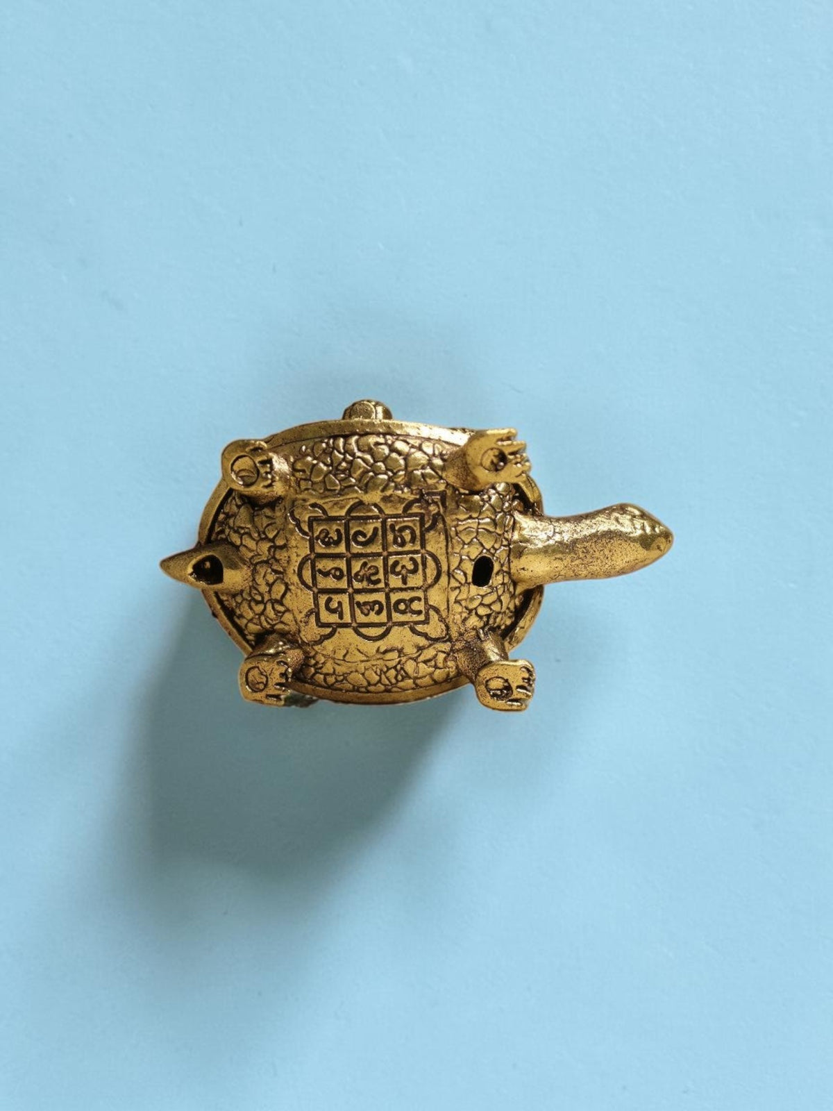 Rigvedaa™ brass tortoise figurine featuring an engraved Shree Yantra on its shell, top-down view on a light blue background.