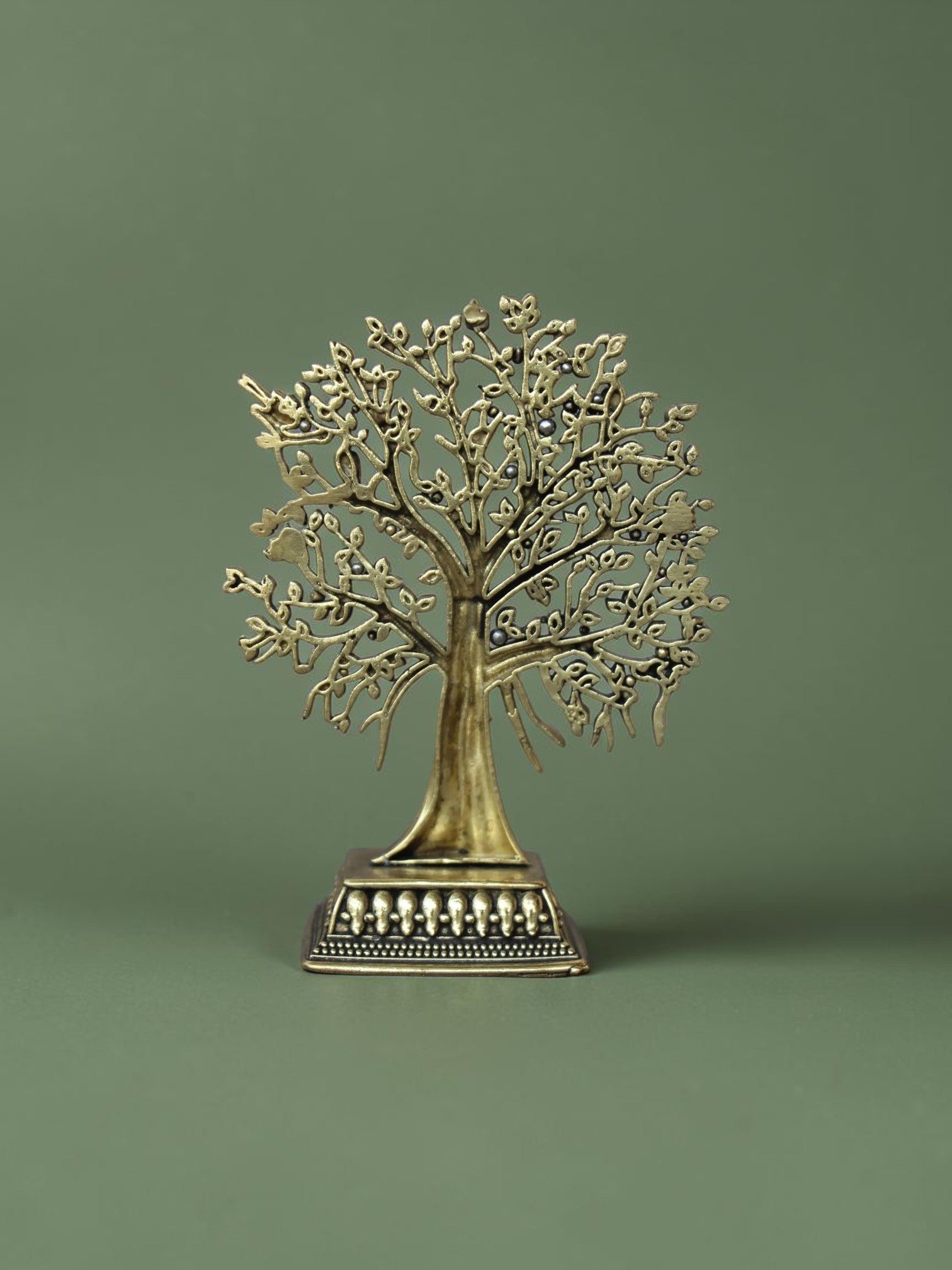 Rigvedaa™ brass Tree of Life tabletop sculpture with intricate branches, leaves, and bird accents on an ornate base.