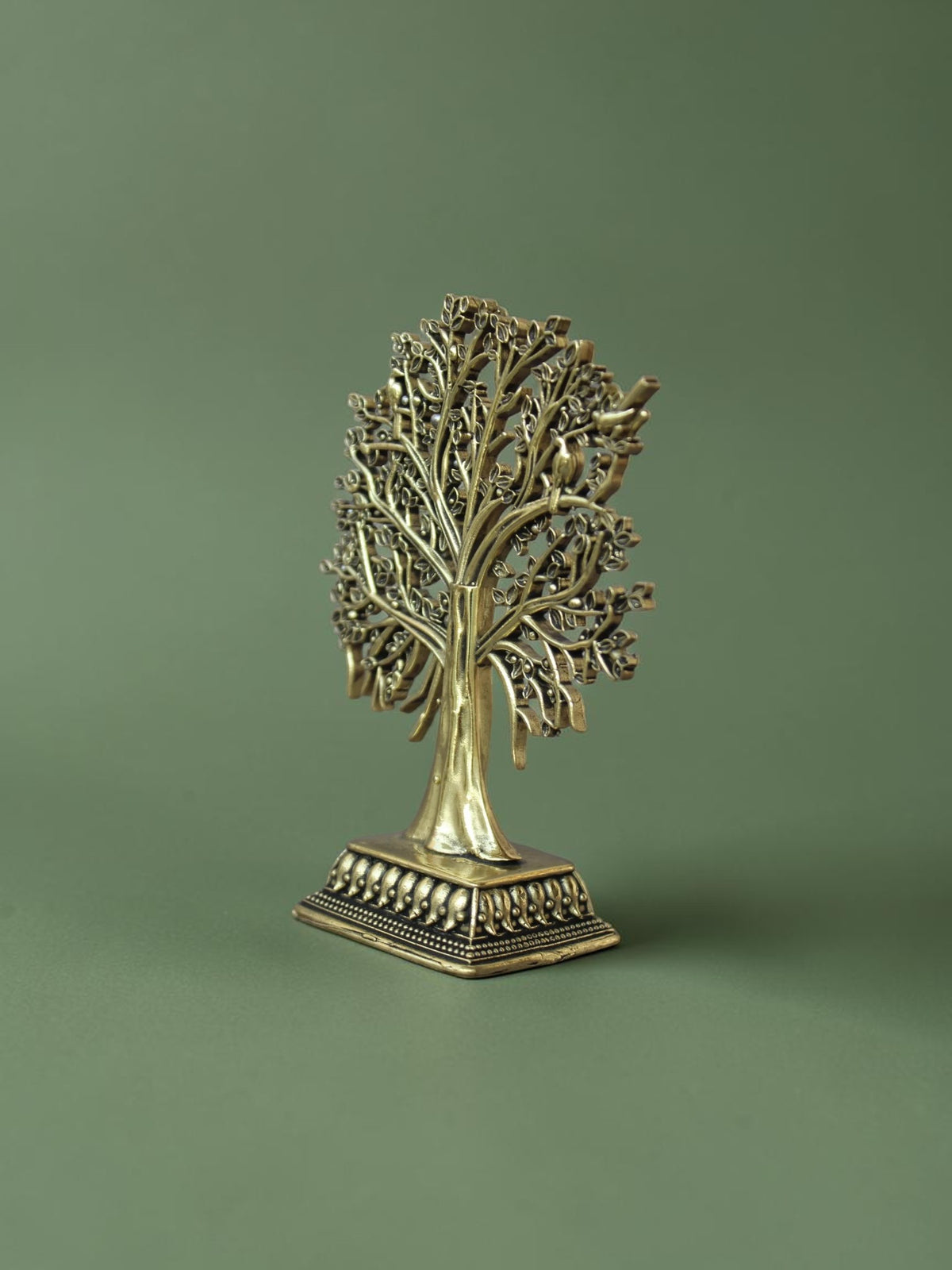 Rigvedaa™ brass Tree of Life tabletop sculpture with intricate branches, leaves, and bird accents on a green background
