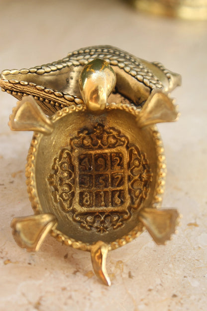 Rigvedaa™ brass Vastu tortoise with intricate detailing and a mystical square on its shell, symbolizing wealth and protection.