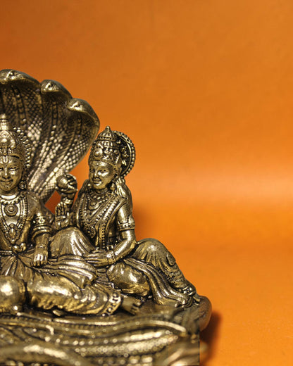 Rigvedaa™ Brass Vishnu Lakshmi Sheshnag statue, golden patina, intricate details, divine couple on serpent.