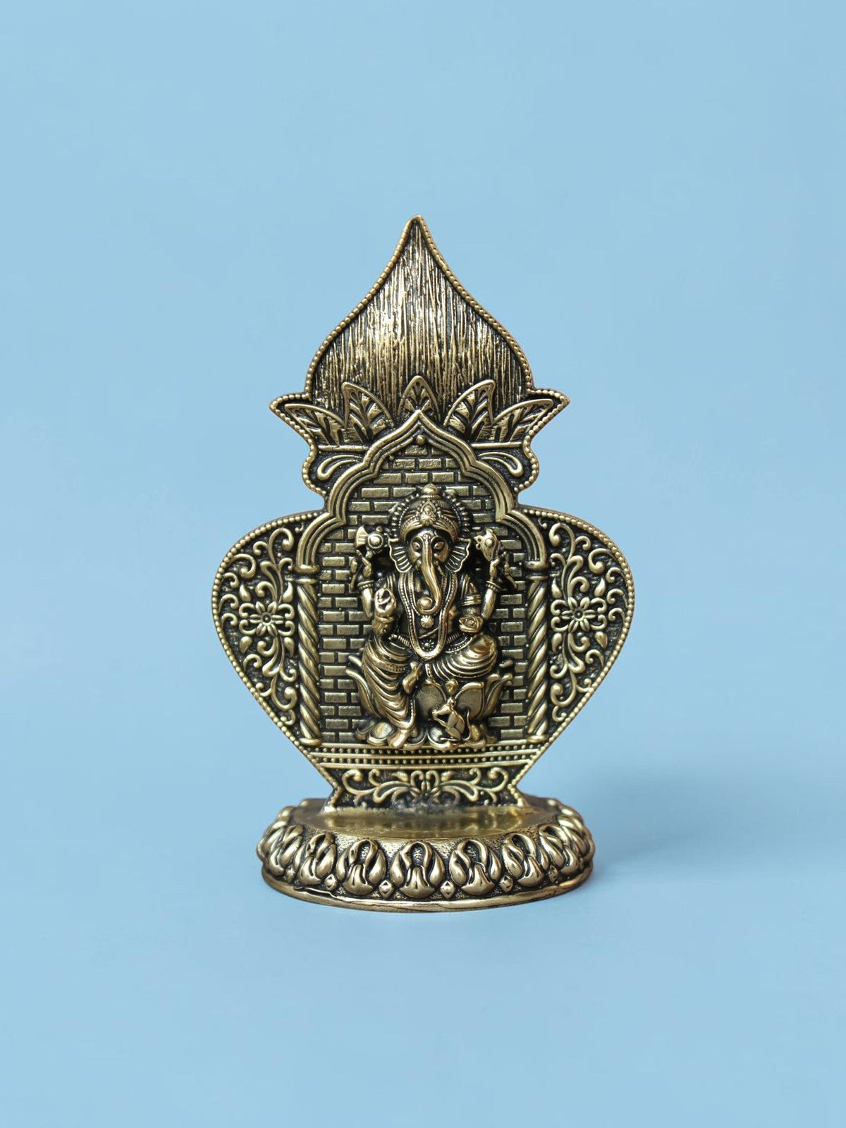 Rigvedaa™ antique gold Ganesha idol in an ornate arch frame with floral motifs and a lotus pedestal on a blue background