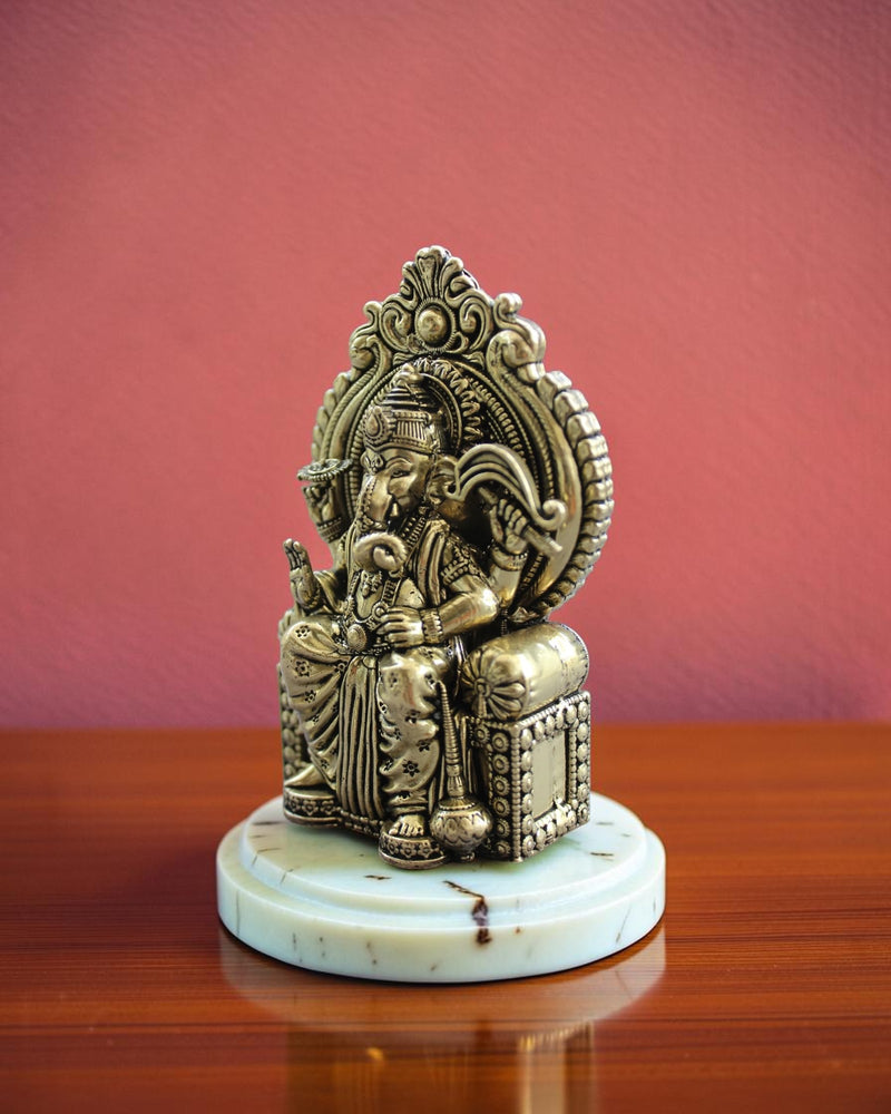 Rigvedaa™ antique brass Ganesha statue seated on an ornate throne, detailed traditional Indian artistry.